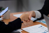 Focus handshake by businessman in formal wear in meeting room after successful agreement or deal. Colleagues shake hands to each other after getting promotion as concept of harmony and unity concept. Poster #657353196