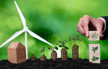 Téléchargez les photos : Homme d'affaires tenant le symbole ESG avec semis sur pile de pièces et éolienne. Environnement gouvernance sociale et responsabilité des entreprises en matière d'énergie durable pour réduire les émissions de CO2 polluant. Modifier - en image libre de droit