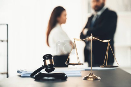 Balanced scale of justice and gavel hammer in focus on blurred background of lawyer colleagues discuss and plan for lawsuit in law firm office, as legal representatives. Equilibrio