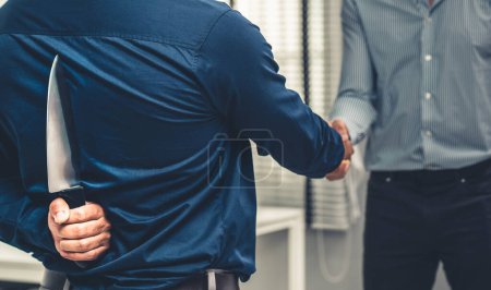 Photo for Back view of businessman shaking hands with another businessman while holding a knife behind his back. Concept of back backstabbing in business, backstabbing between colleagues. - Royalty Free Image