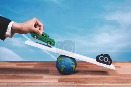 Téléchargez les photos : Homme d'affaires pèse voiture écologique EV à l'échelle par rapport au symbole CO2, la promotion de la voiture d'entreprise zéro émission. Approche durable et équilibrée pour un environnement vert. Véhicule net zéro émission. Modifier - en image libre de droit