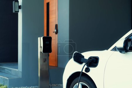 Foto de Progressive concept of EV car and home charging station powered by sustainable and clean energy with zero CO2 emission for green environmental. Charging point at residential area for electric vehicle. - Imagen libre de derechos