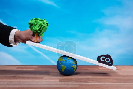 Businessman hold a paper tree on scale against CO2 symbol, promoting forest regeneration by corporate ecology responsibility as sustainable solution to reduce CO2 emission for green environment. Alter