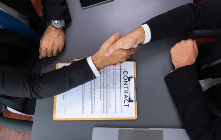 Zwei Profis schließen das Geschäft erfolgreich per Handschlag ab und besiegeln damit den Partnerschaftsvertrag. Rechtliches Dokument und Händeschütteln als formale Vereinbarung zwischen zwei Unternehmen. Inbrünstig