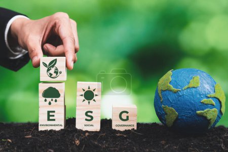 Geschäftsmann hält einen Planeten aus Papier mit einem Holzwürfel mit ESG-Symbol. Nachhaltige Unternehmensentwicklung für Umwelt, Soziales und Governance-Idee zur Rettung der Erde. Alter