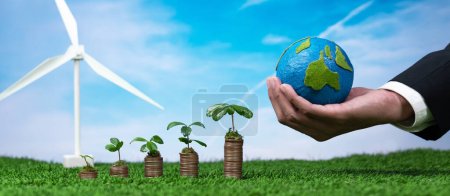 Las empresas ecológicas invierten en subsidios para la conservación del medio ambiente, pila de monedas con plántulas de cultivo, papel de mano Tierra y turbina eólica. Crecimiento financiero sostenible con energía limpia y renovable. Alteración