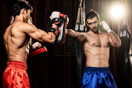 Photo for Asian and Caucasian Muay Thai boxer unleash punch in fierce boxing training session, delivering punching strike to sparring trainer, showcasing Muay Thai boxing technique and skill. Impetus - Royalty Free Image
