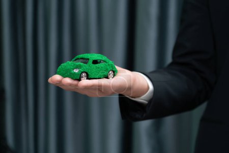Téléchargez les photos : Homme d'affaires tenant éco modèle de voiture verte. Véhicule électrique utilisé par les entreprises respectueuses de l'environnement pour le transport écologique. Entreprise responsable avec zéro émission de CO2. Charmante. - en image libre de droit