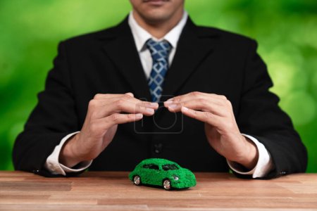 Geschäftsmann decken grüne Öko-Auto-Modell im Büro. Elektrofahrzeuge, die von umweltfreundlichen Unternehmen für umweltfreundlichen Transport genutzt werden. Corporate Responsibility mit null CO2-Emissionen. Alter