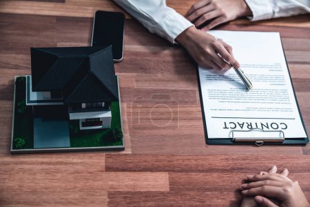 Photo for Top view buyer signs the loan contract paper with a pen on the desk as the completing the final step of the house loan process, securing the ownership of the property. Enthusiastic - Royalty Free Image
