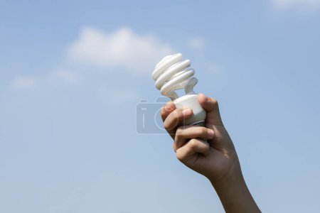 Photo for Recyclable electric waste held in hand up on sky background. Hand holding light bulb for recycle reduce and reuse concept to promote clean environment with recycling management. Gyre - Royalty Free Image