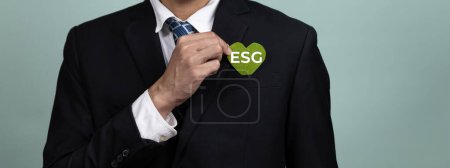 Foto de Corporativo promoviendo el concepto de negocio sostenible y verde con el empresario sosteniendo el papel de símbolo de ESG como compromiso del gobierno social ambiental usando energía limpia con cero emisiones de CO2. Alteración - Imagen libre de derechos