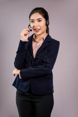 Téléchargez les photos : Opérateur attrayant centre d'appels asiatique féminin avec sourire heureux visage annonce possibilité d'emploi sur l'espace vide, portant un costume formel et casque sur fond isolé personnalisable. Enthousiaste - en image libre de droit
