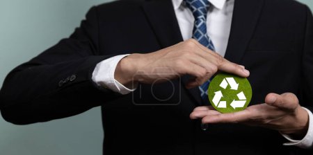 Téléchargez les photos : Entreprise promouvant un concept d'entreprise durable et écologique avec un homme d'affaires tenant le papier symbole Recycler comme Réduire la réutilisation Concept de recyclage pour la gestion des déchets pour une idée d'environnement propre. Modifier - en image libre de droit