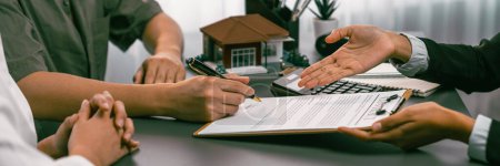 Photo for Panorama view of married couple signing house loan contract with real estate agent. Client customer purchasing new home, sealing the deal with signatures after reviewing terms and agreements. Prodigy - Royalty Free Image