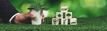Téléchargez les photos : Businessman tenant pot de plante avec symbole ECO cube. Régénération des forêts et sensibilisation à la nature. Entreprise verte éthique avec une politique écologique utilisant les énergies renouvelables pour préserver l'écologie. Modifier - en image libre de droit