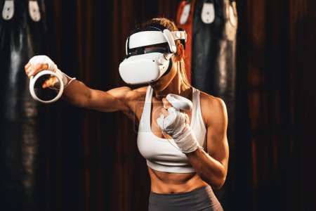 Foto de Entrenamiento de boxeadora femenina con realidad virtual o realidad virtual, con auriculares VR con técnica de entrenamiento de boxeo inmersivo utilizando controlador para mejorar su habilidad en simulador de boxeo. Impulso - Imagen libre de derechos