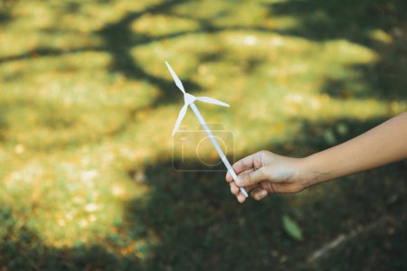 Photo for Little boy holding windmill or wind turbine mockup model to promote eco clean and renewable energy technology utilization for future generation and sustainable Earth. Gyre - Royalty Free Image