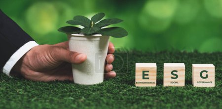 Photo for Businessman holding plant pot with ESG cube symbol. Forest regeneration and natural awareness. Ethical green business with eco-friendly policy utilizing renewable energy to preserve ecology. Alter - Royalty Free Image