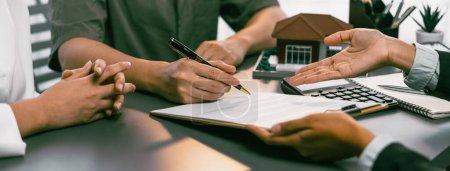 Photo for Panorama view of married couple signing house loan contract with real estate agent. Client customer purchasing new home, sealing the deal with signatures after reviewing terms and agreements. Prodigy - Royalty Free Image