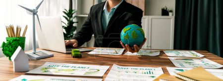Téléchargez les photos : Homme d'affaires ou PDG de la société verte détenant du papier Earth comme concept d'entreprise respectueuse de l'environnement pour réduire les émissions de CO2 et l'empreinte carbone pour l'écologie propre. Des pionniers - en image libre de droit