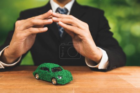 Photo for Businessman cover green eco car model in office. Electric vehicle utilized by eco-friendly business for environmental friendly transportation. Corporate responsible with zero CO2 emission. Alter - Royalty Free Image