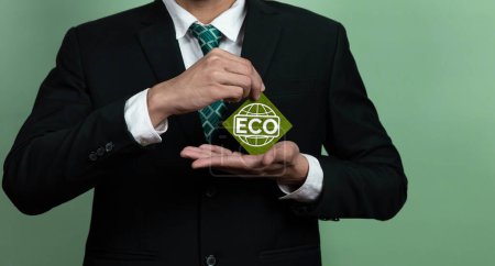 Photo for Eco-friendly corporate promoting sustainable and green business concept with businessman hold ECO symbol paper as environmental protection commitment using clean energy with zero CO2 emission. Alter - Royalty Free Image