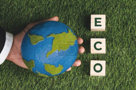 Photo for Top view businessman hand hold wooden cube with eco symbol and paper globe on grass background. Environmental awareness and sustainable energy. Clean and renewable energy for greener ecology. Alter - Royalty Free Image