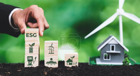 Photo for Businessman put ESG symbol cube with house and wind turbine model. Concept for forest regeneration by ethical corporate company with environmental awareness for green environment in future. Alter - Royalty Free Image