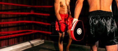 Photo for Asian and Caucasian Muay Thai boxer unleash punch in fierce boxing training session, delivering punching strike to sparring trainer, showcasing Muay Thai boxing technique and skill. Spur - Royalty Free Image