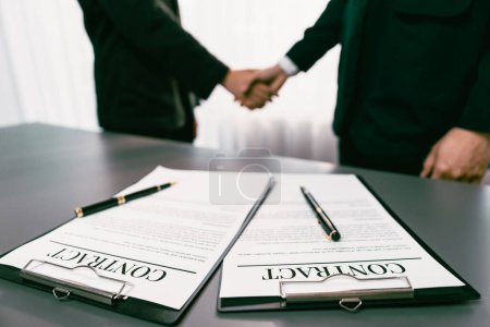 Photo for Focus closeup panorama business contract paper with pen, while two professionals shake hand in blurred background, signifying successful negotiation and partnership agreement with handshaking. Prodigy - Royalty Free Image