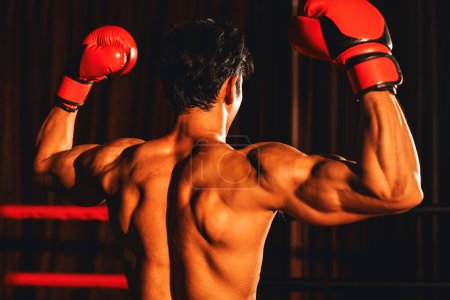 Foto de Vista trasera del victorioso boxeador Muay Thai golpea pose triunfante, disfrutando de la gloria de su victoria duramente ganada mostrando orgullosamente su cuerpo fuerte y musculoso. Impulso - Imagen libre de derechos