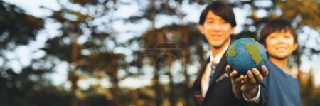Photo for Focus panorama Earth with blur asian boy and businessman holding globe together as Earth day concept. Corporate social responsible to make greener environmental for sustainable future generation. Gyre - Royalty Free Image