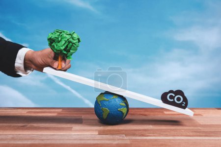 Photo for Businessman hold a paper tree on scale against CO2 symbol, promoting forest regeneration by corporate ecology responsibility as sustainable solution to reduce CO2 emission for green environment. Alter - Royalty Free Image