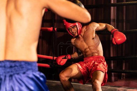 Photo for Boxer fighter with boxing helmet in fierce and intense fight while the competitor struggling to fight with his back against the ring displaying resilience and determination. Impetus - Royalty Free Image