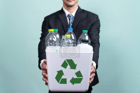 Foto de Empresario mantenga la papelera de reciclaje llena de botella de plástico sobre un fondo aislado. Responsabilidad corporativa por el medio ambiente verde y la comunidad. Concepto de separación y gestión de residuos. Alteración - Imagen libre de derechos