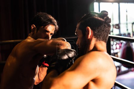 Photo for Asian and Caucasian Muay Thai boxer unleash elbow attack in fierce boxing match. Thai boxer with strong muscular body exchanging punch and elbow strike with relentless combat prowess. Impetus - Royalty Free Image