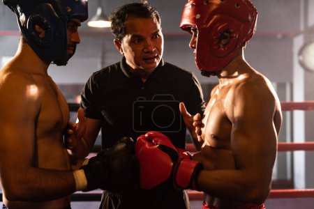 Photo for Boxer fighter with safety helmet or head guard face off with each other while referee explain rules of engage to competitor before start boxing match on the ring. Impetus - Royalty Free Image
