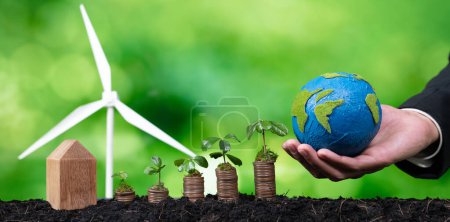 Photo for Eco business invest on environment conservation subsidize, coin stack with grow seedling, hand holding paper Earth and wind turbine. Sustainable financial growth with clean and renewable energy. Alter - Royalty Free Image