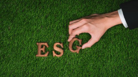 Photo for Environmental awareness campaign showcase message arranged by hand in ESG on biophilic green grass background. Environmental social governance concept idea for sustainable and greener future. Gyre - Royalty Free Image