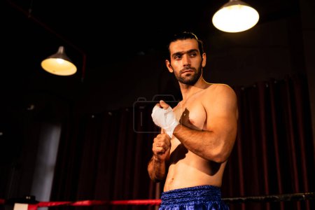 Photo for Caucasian boxer portrait with muscular and athletic body wrapping his hand or fist on the ring be fore the boxing fight match or training. Impetus - Royalty Free Image