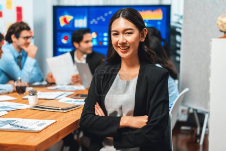 Téléchargez les photos : Portrait d'une jeune femme d'affaires asiatique heureuse ou analyste regardant la caméra avec son collègue analyser l'analyse des données dans une réunion dynamique de planification des investissements en stratégie d'entreprise. Habillement - en image libre de droit