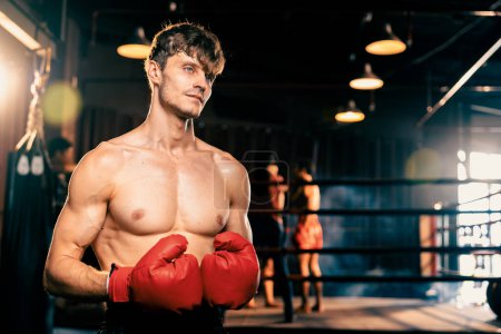 Photo for Boxing fighter shirtless posing, caucasian man boxer wearing red glove in defensive guard stance ready to fight and punch at gym with ring and boxing equipment in background. Impetus - Royalty Free Image