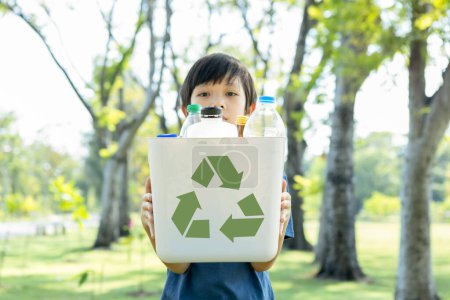 Photo for Cheerful young asian boy holding recycle symbol bin on daylight natural green park promoting waste recycle, reduce, and reuse encouragement for eco sustainable awareness for future generation. Gyre - Royalty Free Image