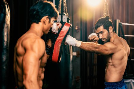 Photo for Asian and Caucasian Muay Thai boxer unleash punch in fierce boxing training session, delivering punching strike to sparring trainer, showcasing Muay Thai boxing technique and skill. Impetus - Royalty Free Image