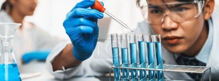 Photo for Group of dedicated scientist conduct chemical experiment in medical laboratory, carefully drop precise amount of liquid from pipette into test tube for vaccine drug or antibiotic development. Neoteric - Royalty Free Image