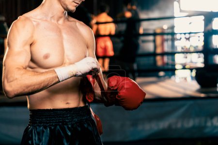 Téléchargez les photos : Boxeur masculin caucasien déterminé avec muscularity corps de préparation physique enveloppe sa main et les dons ou porter un gant de boxe, se préparant à un entraînement intense de boxe sur le ring à la salle de gym. Impulsion - en image libre de droit