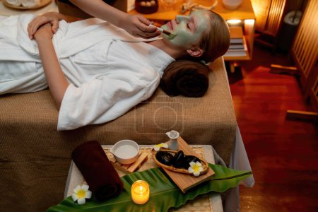 Photo for Serene ambiance of spa salon, woman customer indulges in rejuvenating with luxurious face cream massage with warm lighting candle. Facial skin treatment and beauty care concept. Quiescent - Royalty Free Image