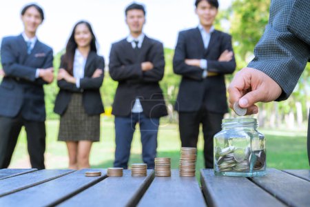 Photo for Businessman put coin to money saving glass jar on outdoor table with coin stack as sustainable money growth investment or eco-subsidize for corporate promoting environmental awareness. Gyre - Royalty Free Image