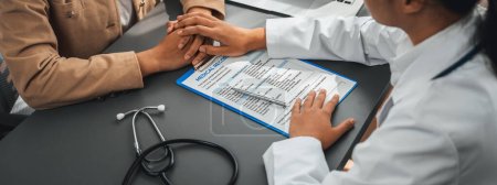 Photo for Doctor show medical diagnosis report and providing compassionate healthcare consultation while holding young patient hand for being supportive and professional in doctor clinic office. Neoteric - Royalty Free Image